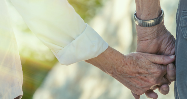 close up of two older people holding hands.