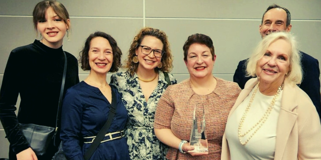 Amy Schwartz-Wallace, holding NYSBA Vanguard Award in her hand. Amy is flanked by several other attendees.
