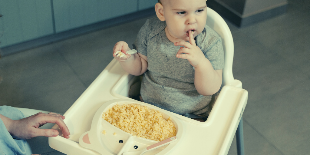 A toddler eating pasta